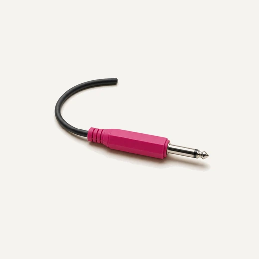 A single unplugged instrument jack with a magenta body, its cable tail curling away.