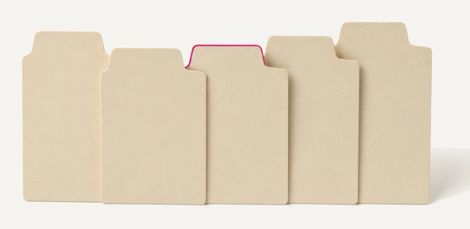 Five blank card-index dividers standing in a row, their raised tabs stepping across at different positions, one tab edged in magenta.