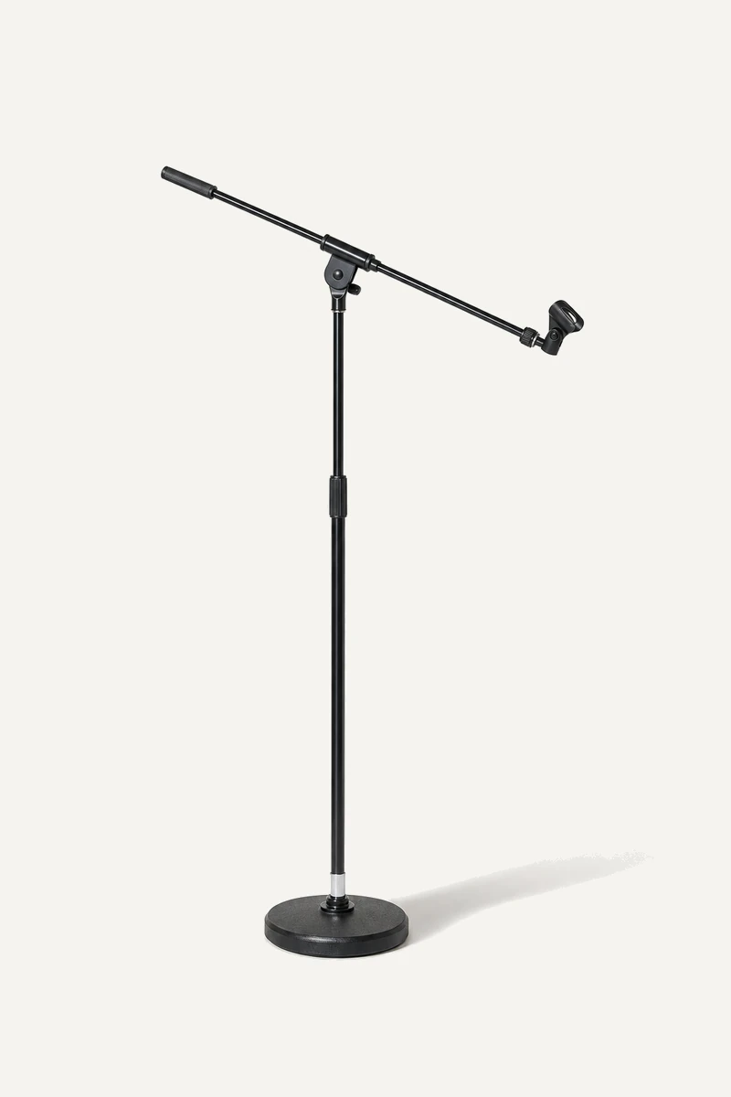 A microphone stand with an empty clip, casting a long shadow.