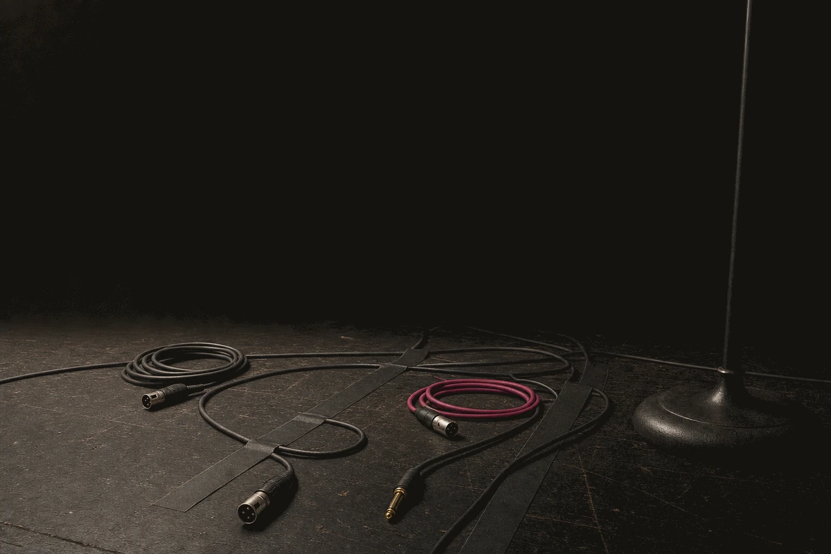Cables coiled and taped down across a bare stage floor after load-in.